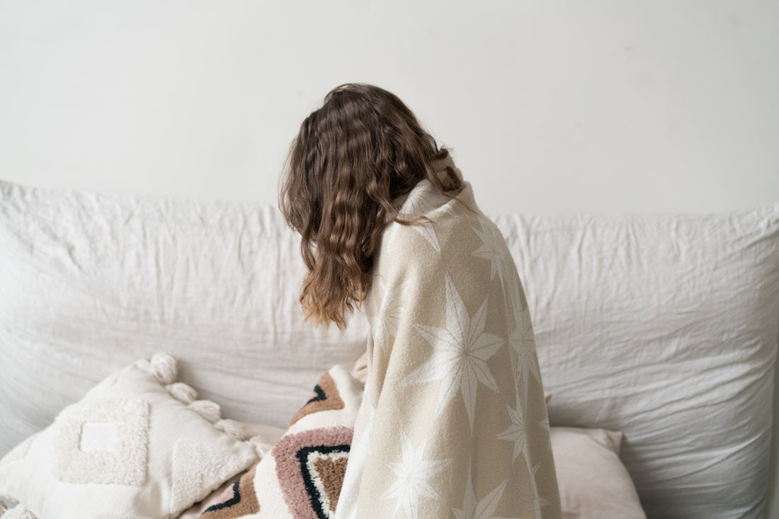 a woman sitting on a couch with a blanket