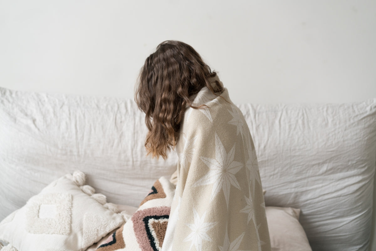 a woman sitting on a couch with a blanket