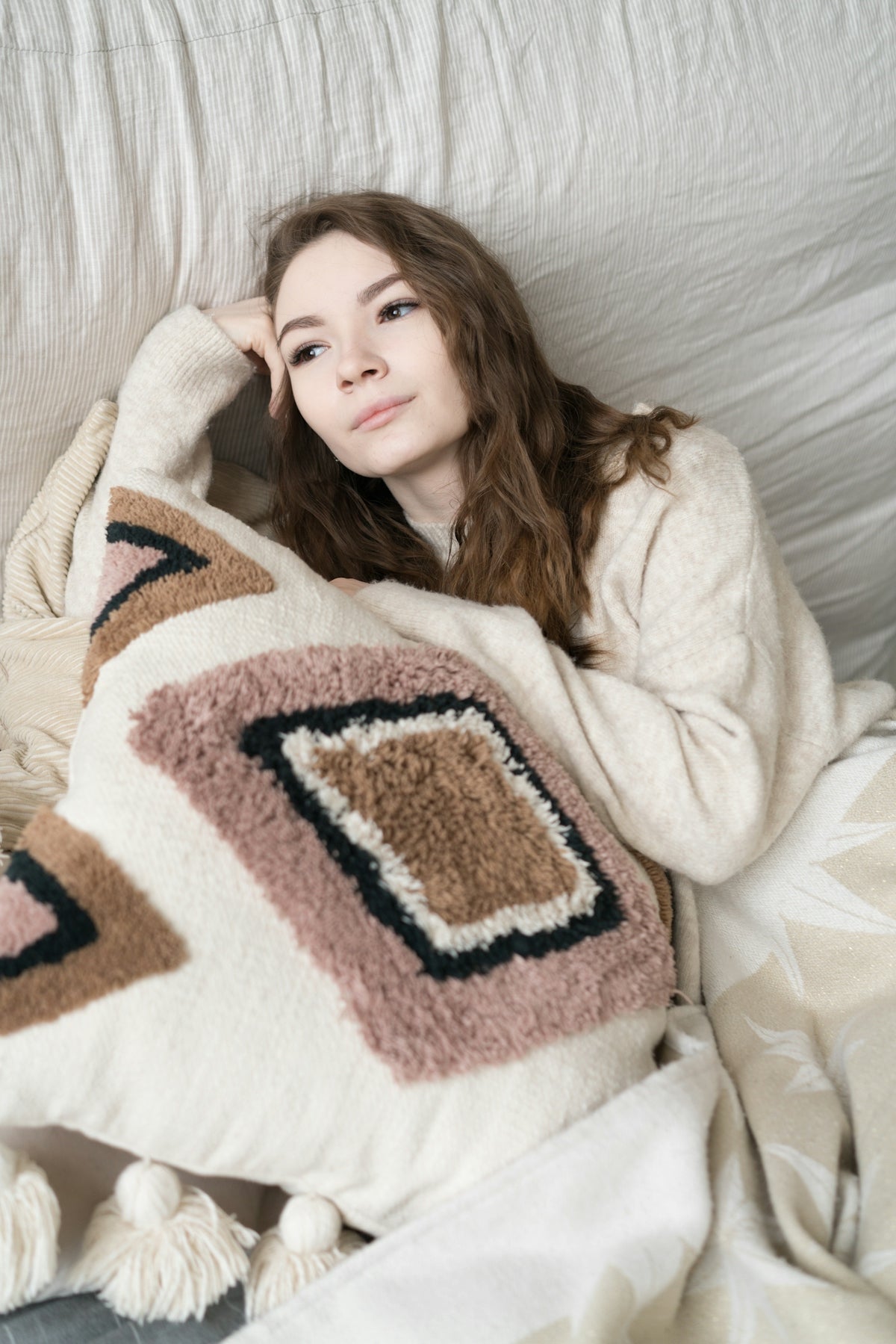 a woman laying on top of a bed under a blanket