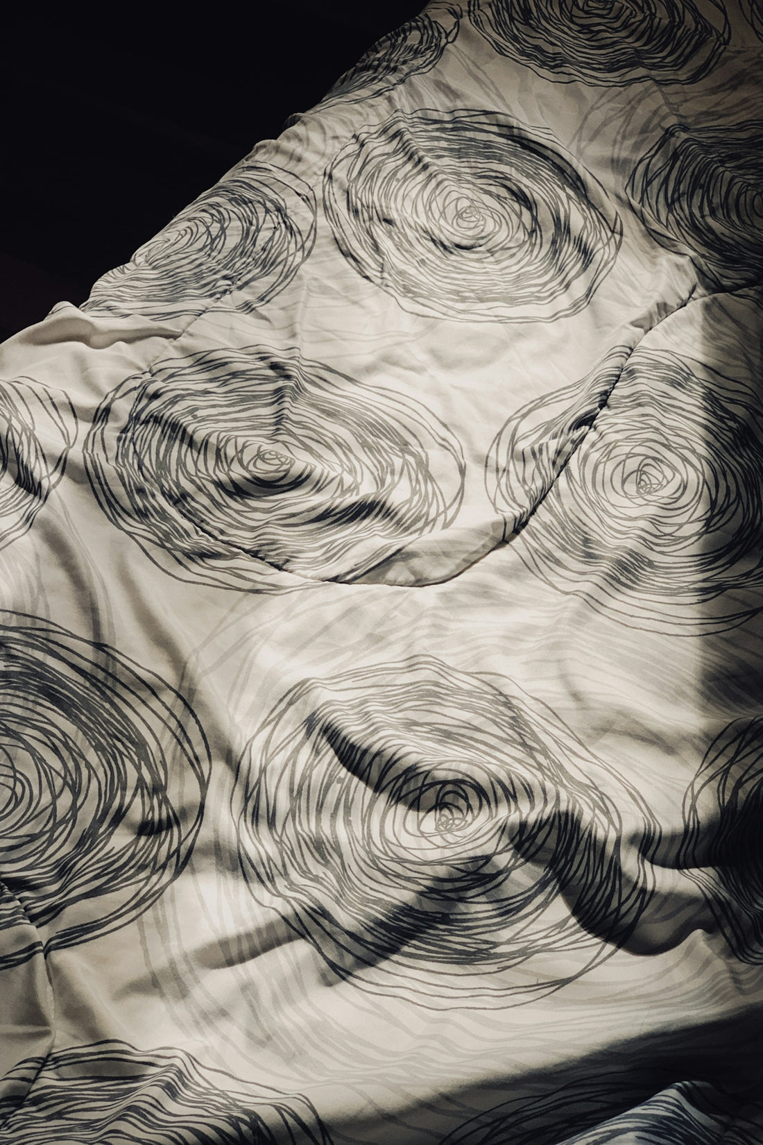 a black and white photo of a bed with a comforter