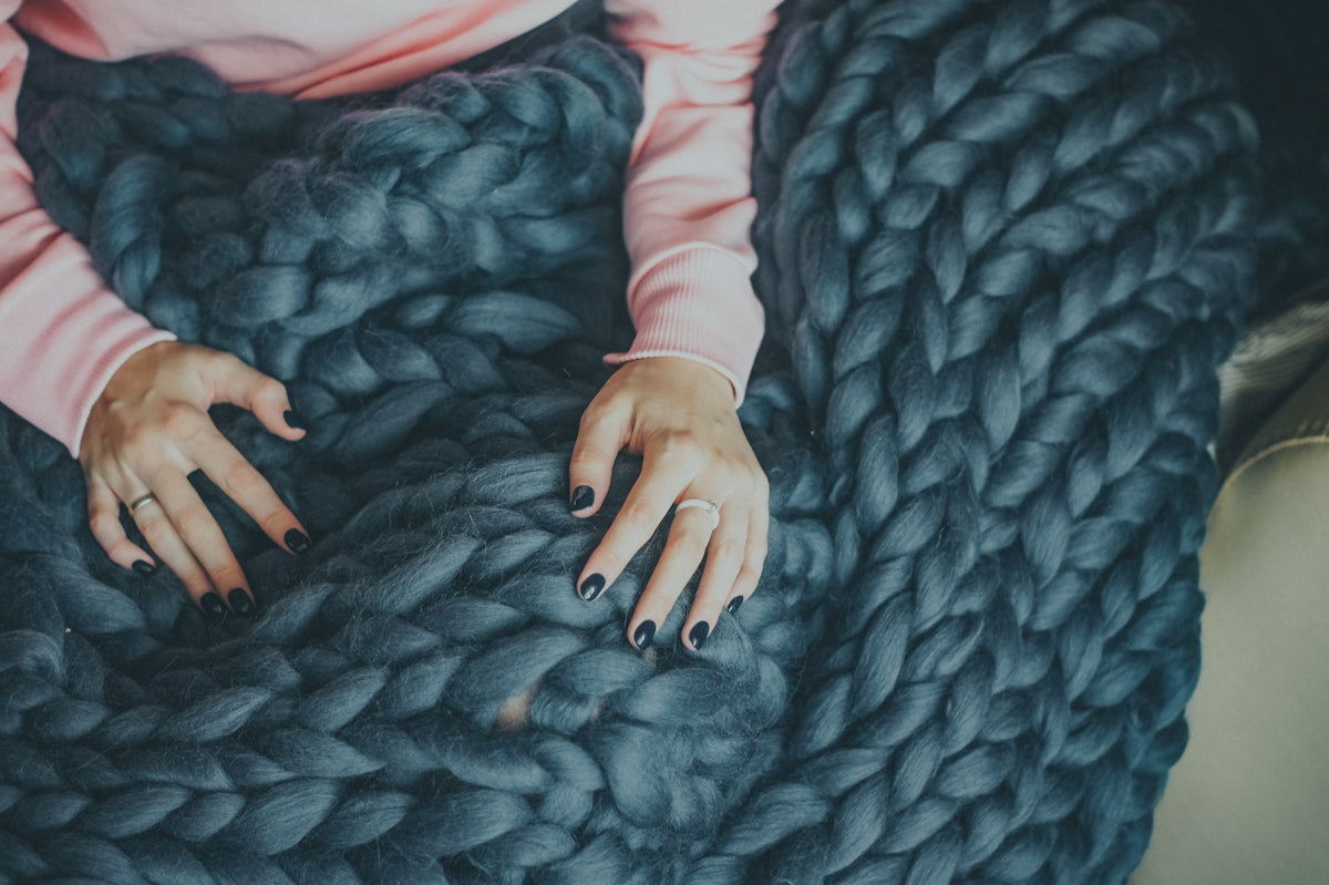 a woman is sitting on a large chunky blanket