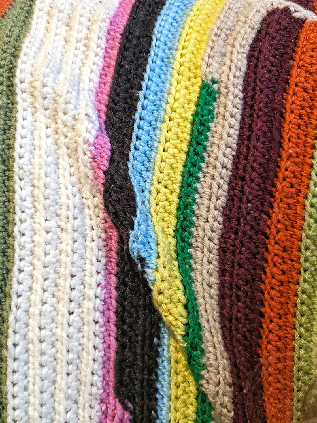 a pile of crocheted blankets sitting on top of a bed