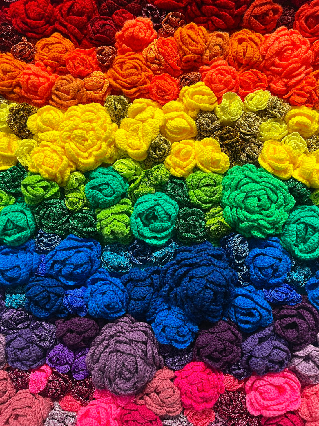 A multicolored crocheted blanket with flowers on it