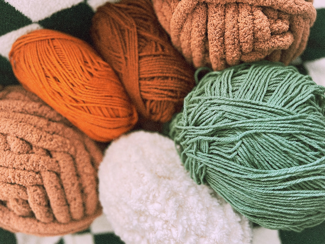 A bunch of balls of yarn sitting on top of a blanket