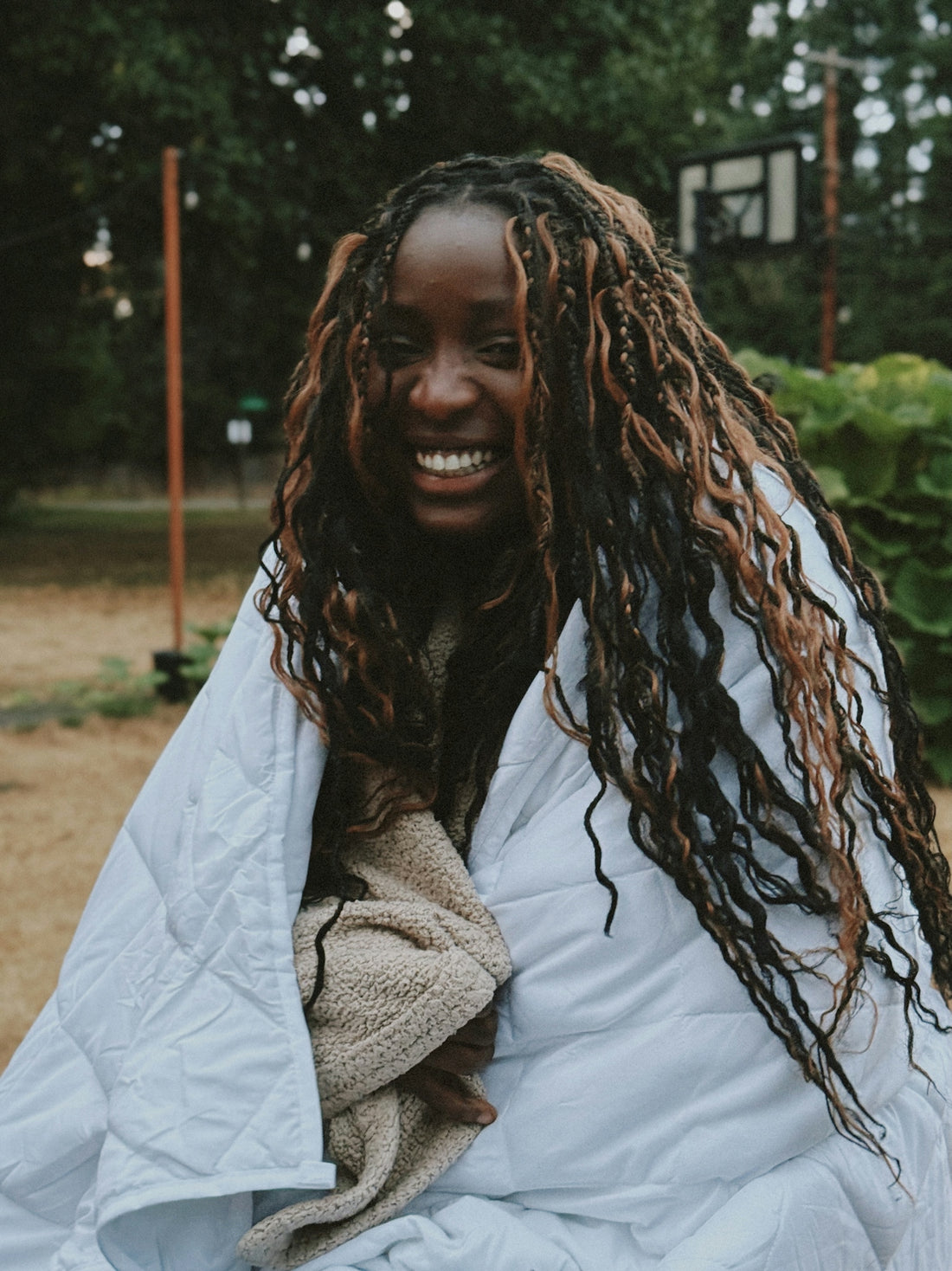 A smiling woman wrapped in a white blanket