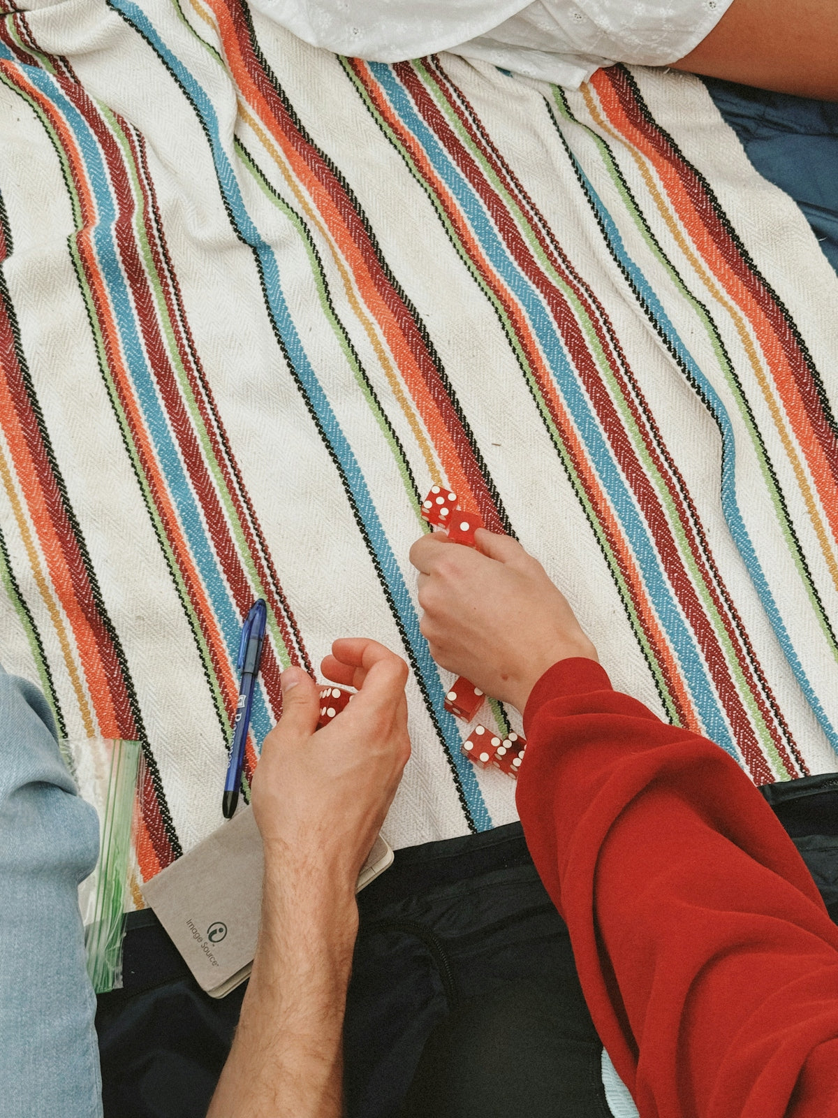 Hands playing with poker chips on a striped blanket