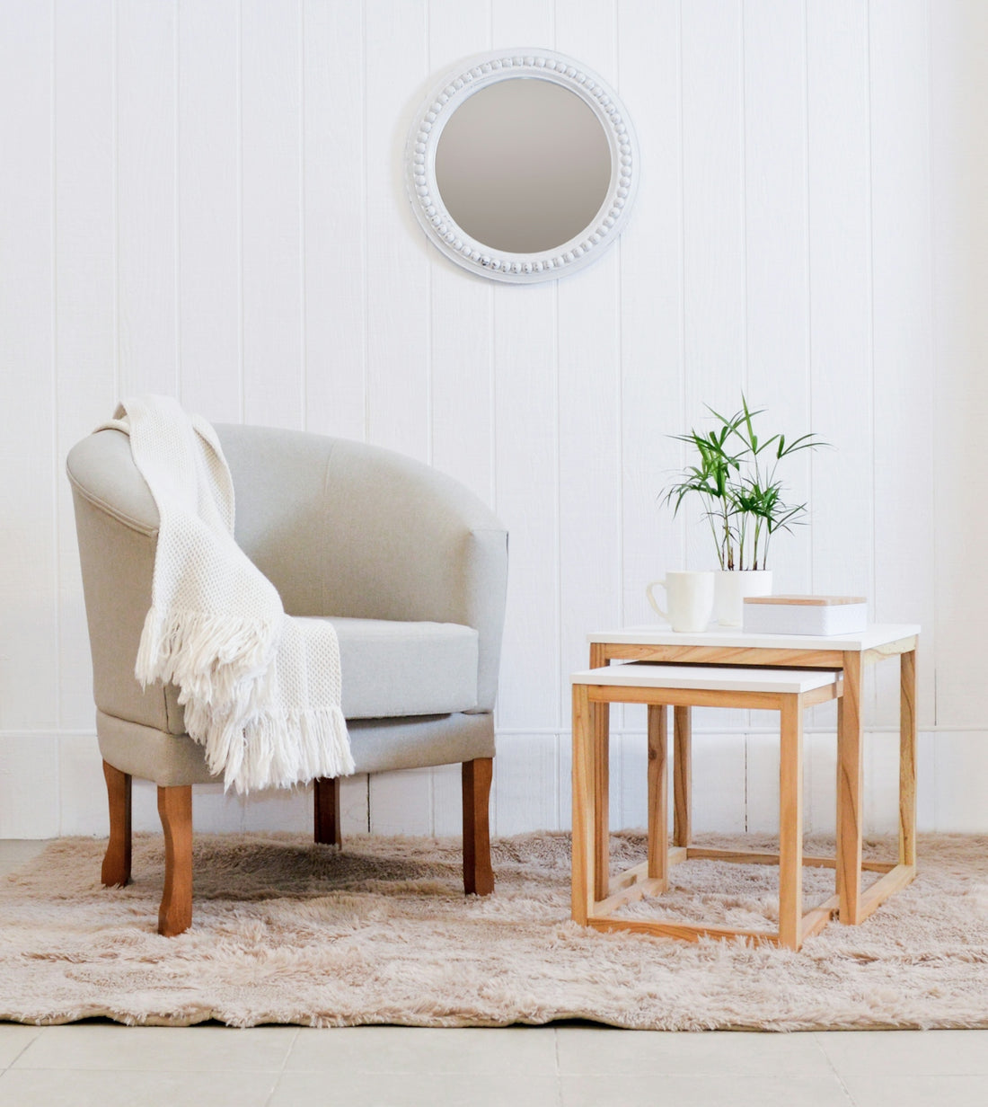A cozy armchair with a throw blanket and side tables.